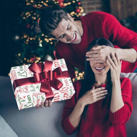 A couple opening a Christmas gift with personalized wrapping paper
