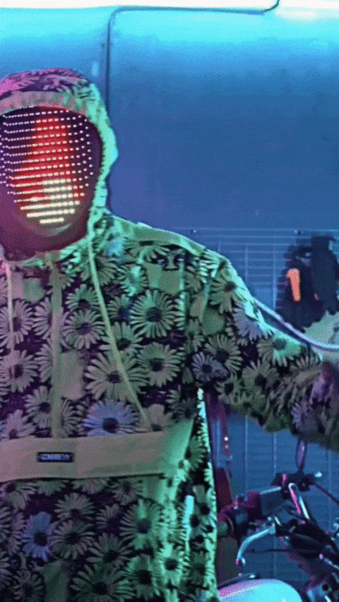 A guy wearing a light up Halloween mask with flames on it and dancing.